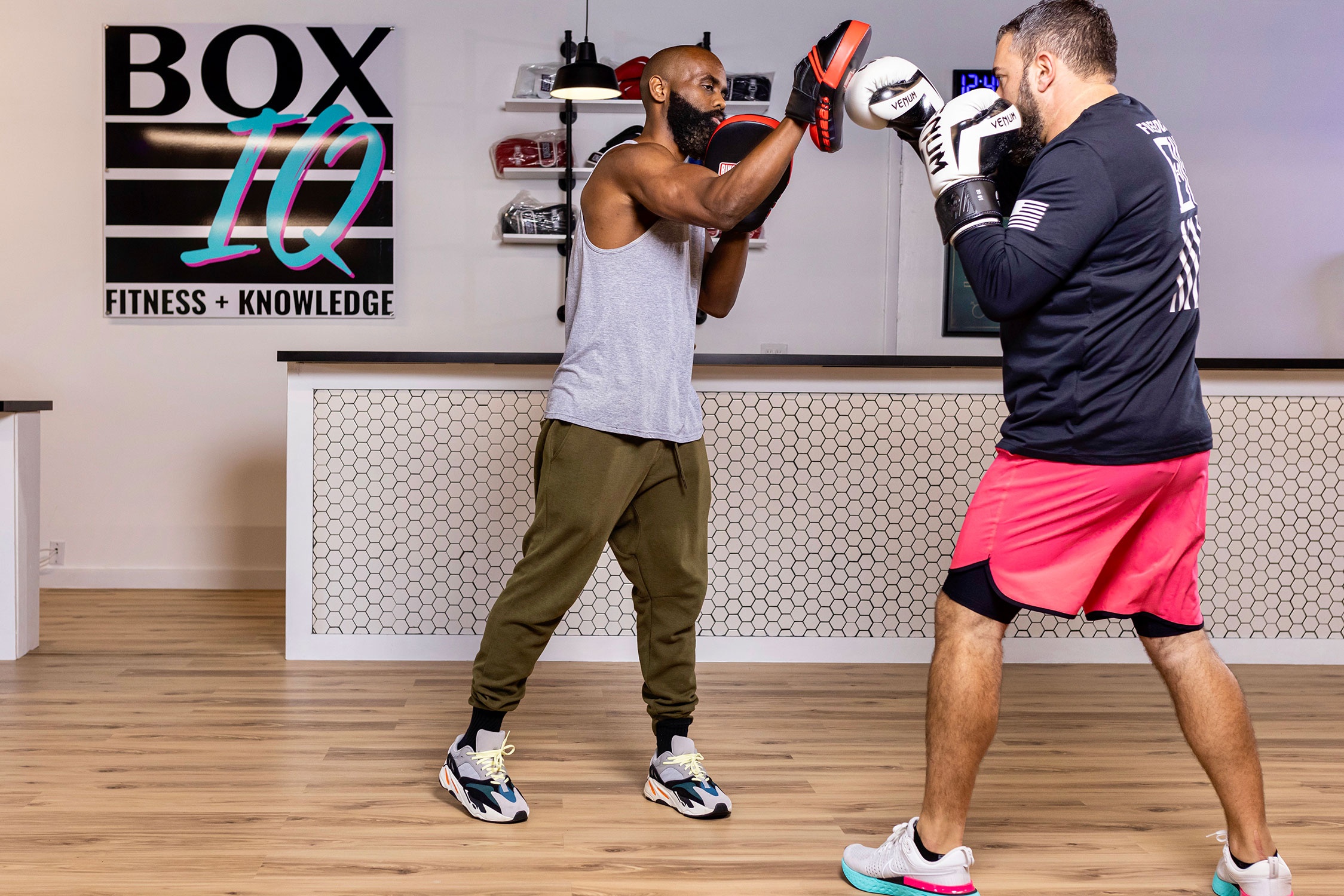 Boxing instructor Ely Honore wearing boxing punch hand pads training with boxing gym member