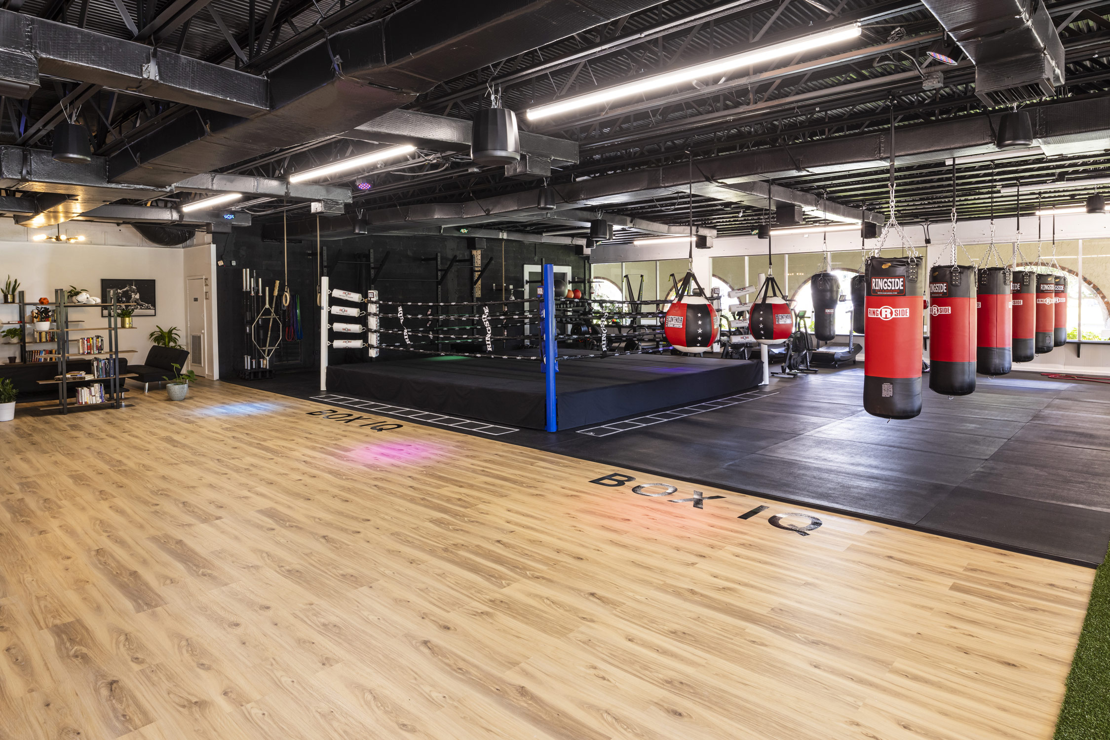 Interior of boxing gym with punching bags and boxing ring in view