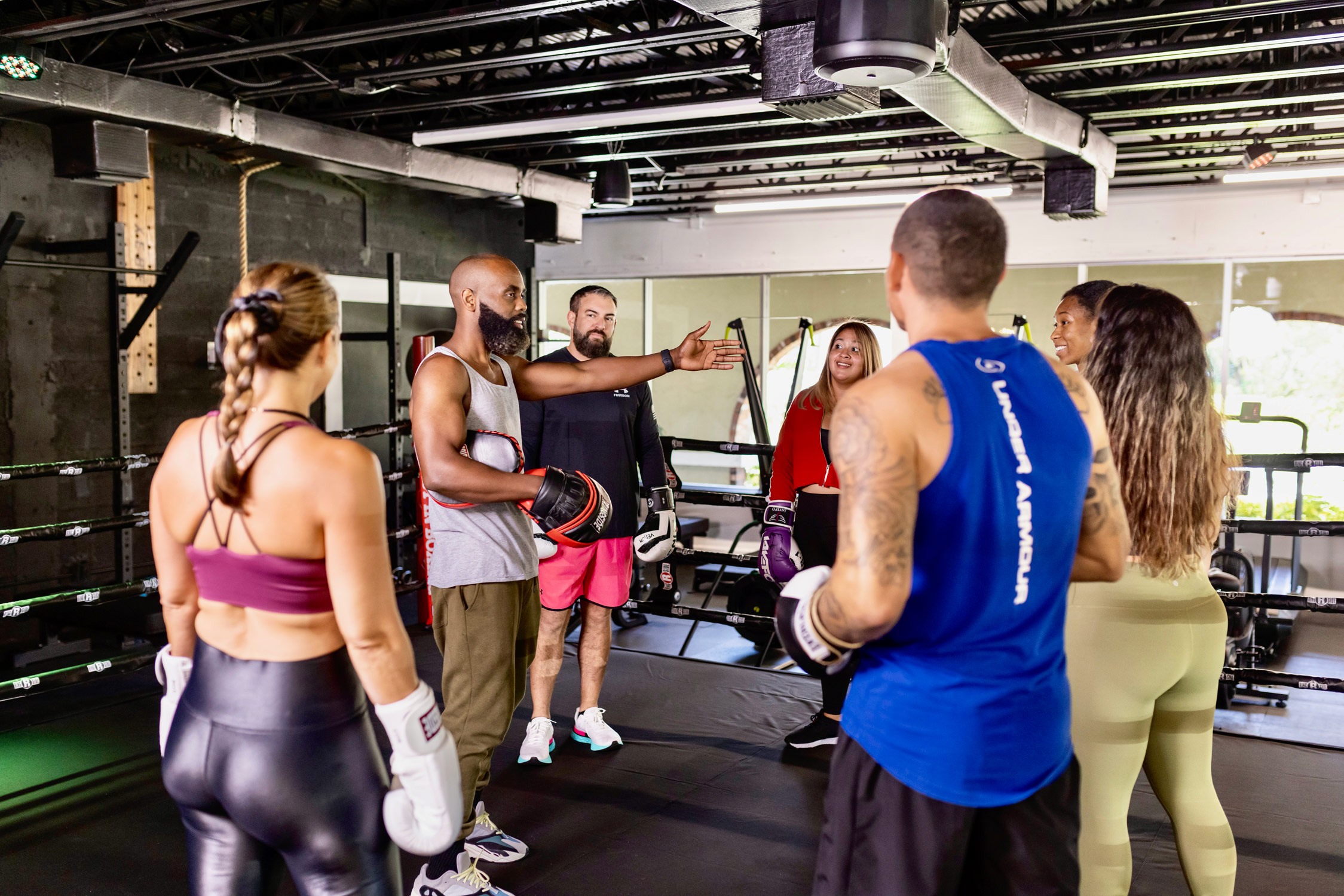Boxing instructor and gym members in a boxing ring at a gym in Palmetto Bay, Miami, Florida