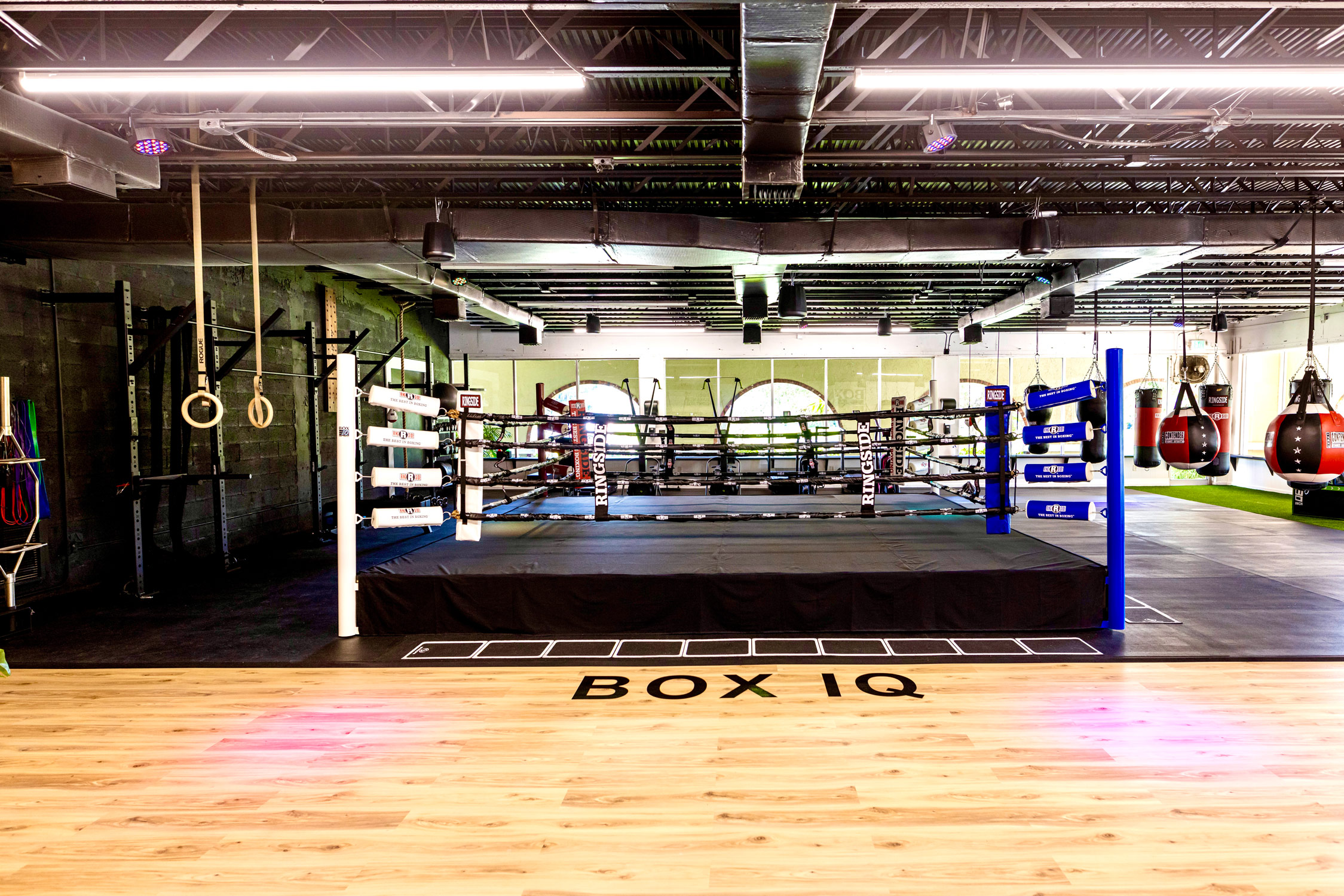 Boxing ring in a gym with gymnastics rings and punching bags in view